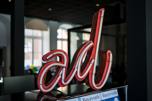 A neon red sign that is turned off. It reads: “ad” in cursive letters.