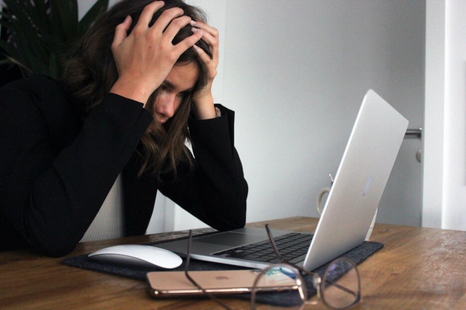 A graphic designer grabs her head while looking at a design on her Macbook.