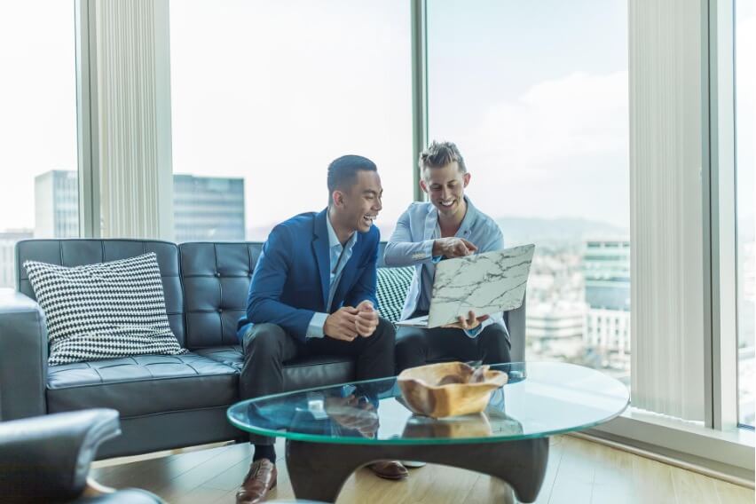 A social media company employee sits with a client and showcases past testimonials.