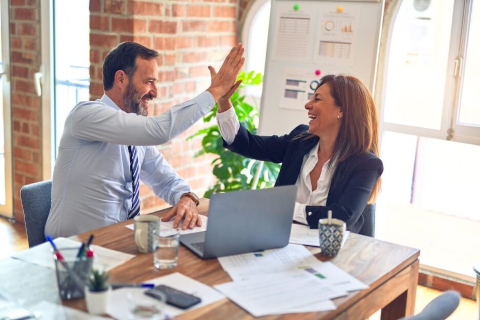 An agency worker and client celebrate after a social media goal is reached.