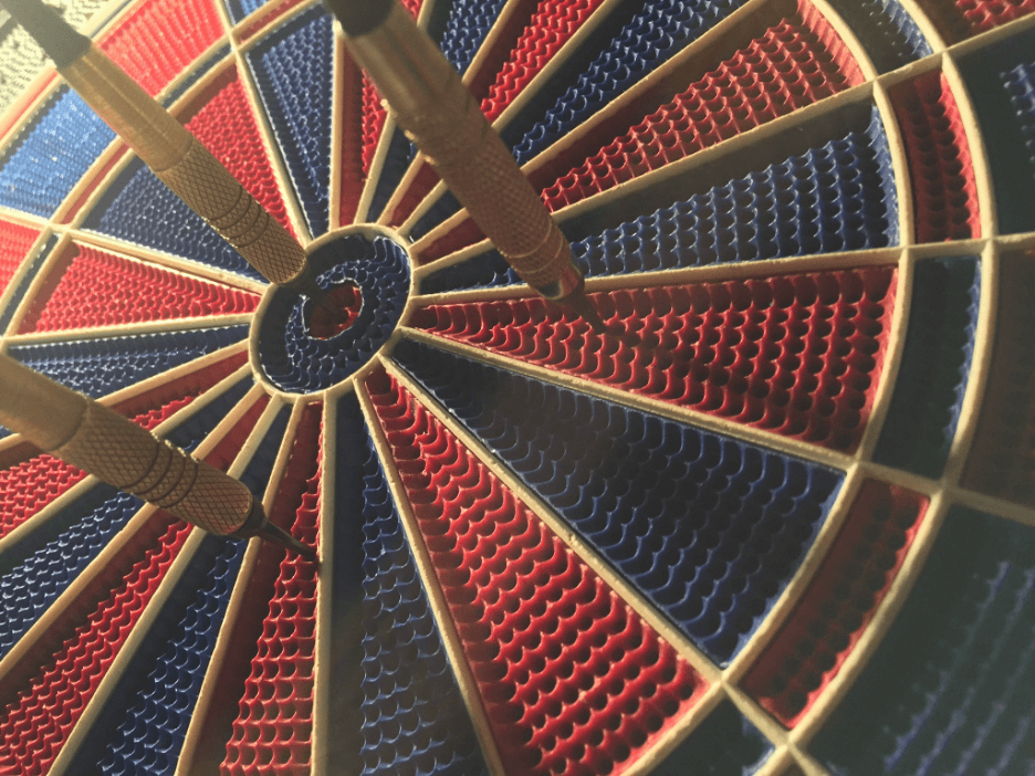 This is an image of a blue and red dartboard. There are three darts on the board with one that hit the bullseye.