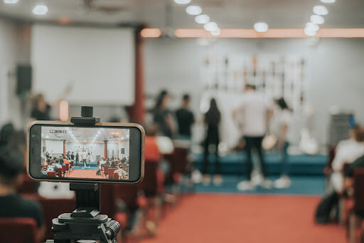 An iPhone on a tripod capturing a live stream of an event for an audience.