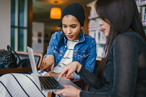 A woman using their laptop to show her Instagram account to another woman.