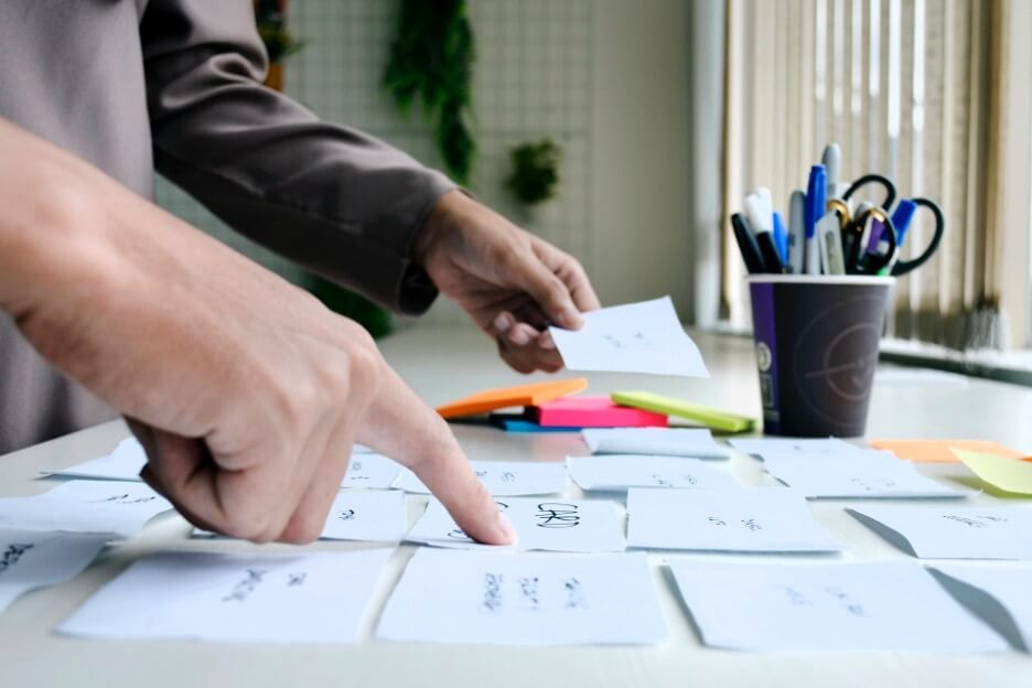 Two people look at several sticky notes placed on an ivory-colored table.