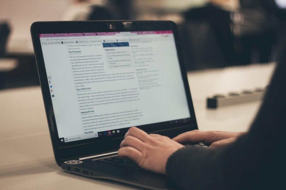 In this image, a content creator writes an article on a black laptop.