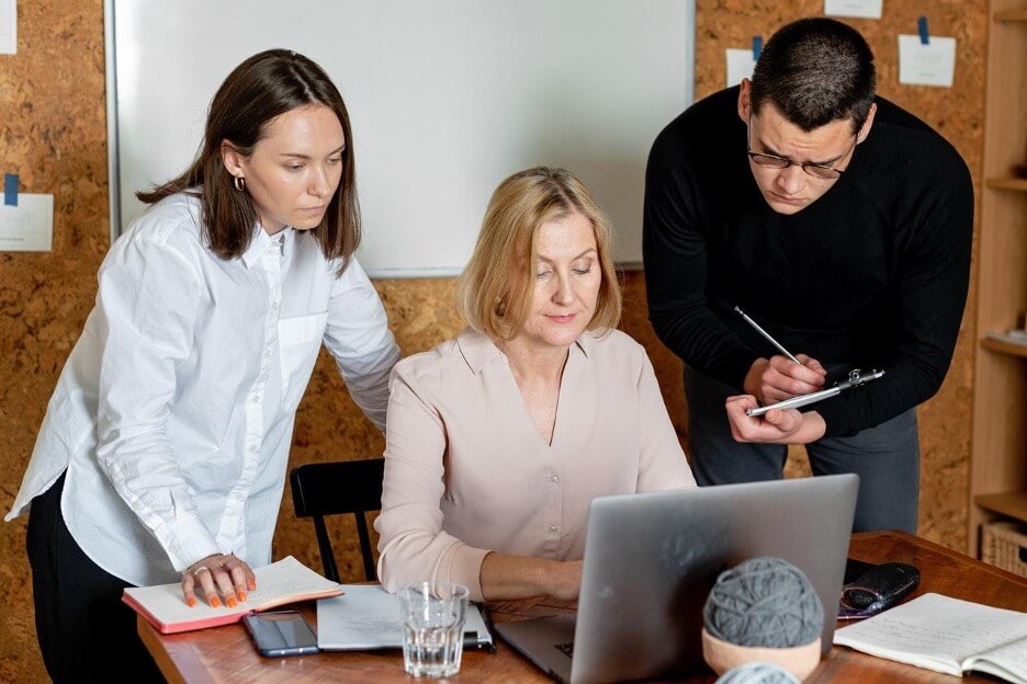 Three digital marketing employees discuss some strategy and take notes of a campaign for a new client.