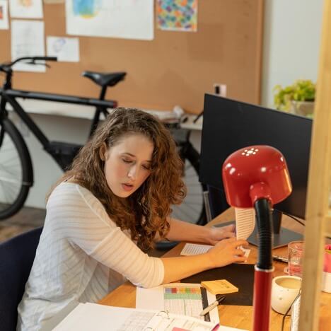 A digital marketing employee checks the performance metrics for her clients and writes them down on a notepad.