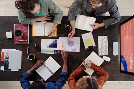 Four digital marketing employees sit around a table and discuss metrics for a client.