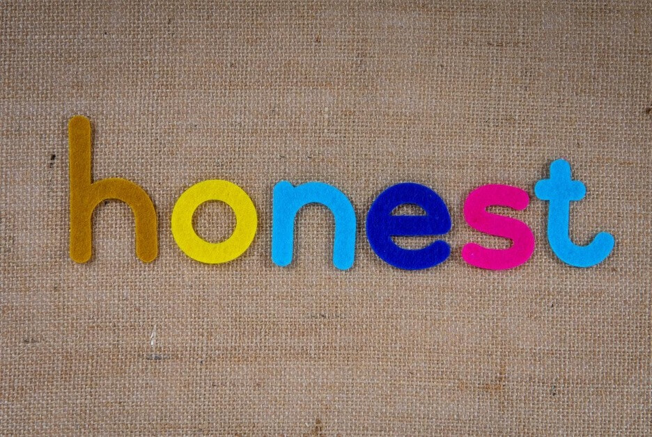 This is an image of letters spelling out “honest” in different colors on top of a brown canvas background.
