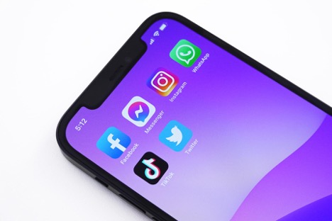 This is an image of an iPhone with a purple background and six social media apps on its home screen.