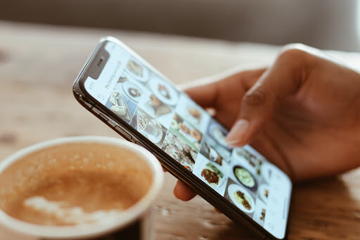  A person using their phone and browsing through Instagram while drinking coffee