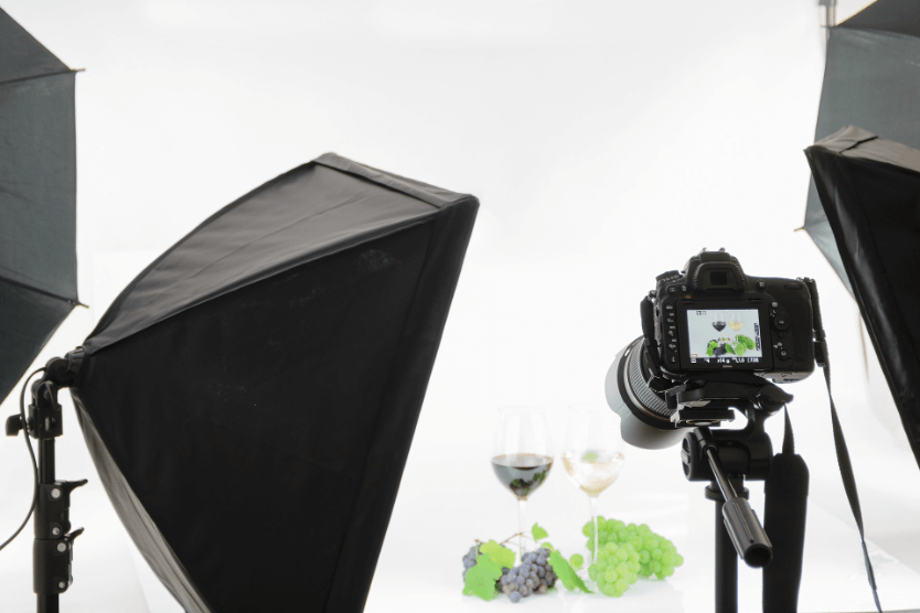 This is an image of a product placement photoshoot promoting two different types of wines. A camera is aimed at two glasses of wine placed on a table.