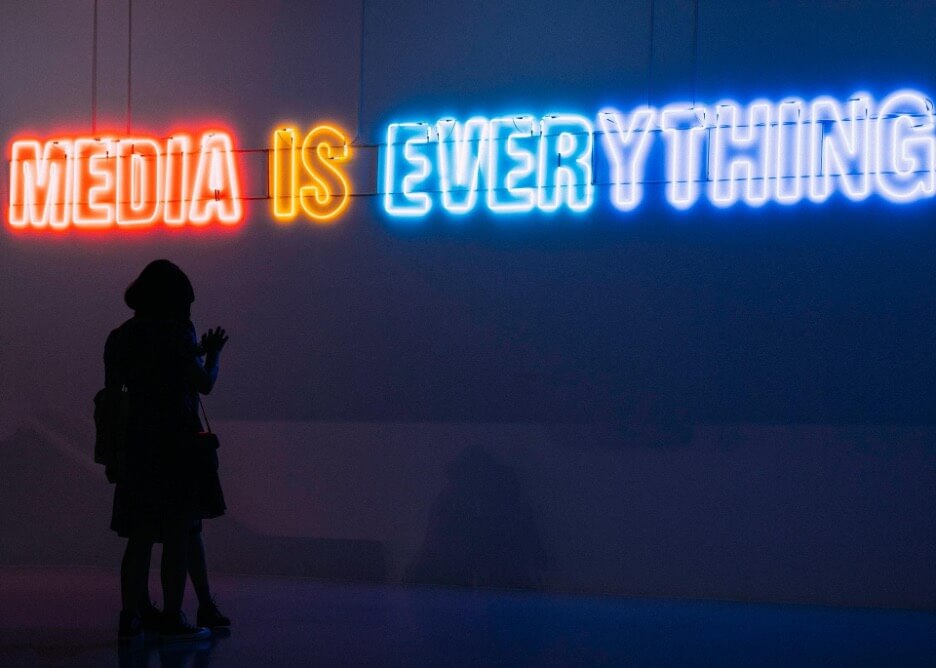 This is an image of a neon banner with the words that read: “media is everything” in red, yellow, and blue.