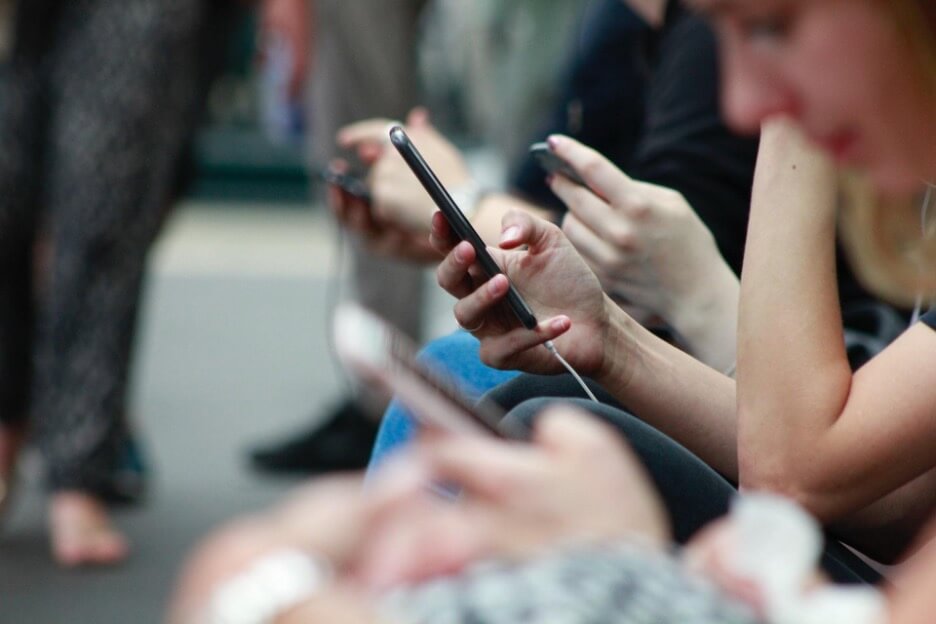 A group of people look at social media on their smartphones.