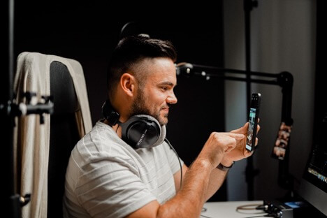 A social media content creator checks the quality of a post he created on his phone.