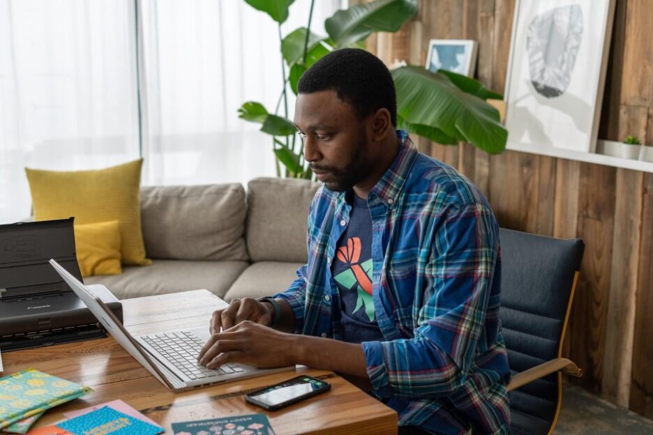 A social media marketer uses his laptop to create a LinkedIn newsletter for a client.