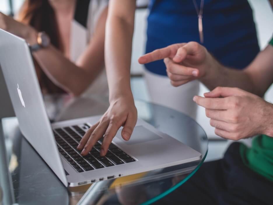 Two social media marketers edit and work on a strategy for a client on a Macbook.