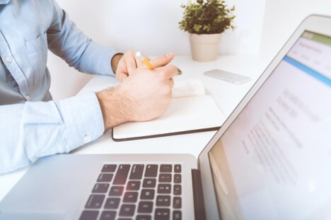 A social media marketing director takes notes in a notebook of potential content for a campaign.