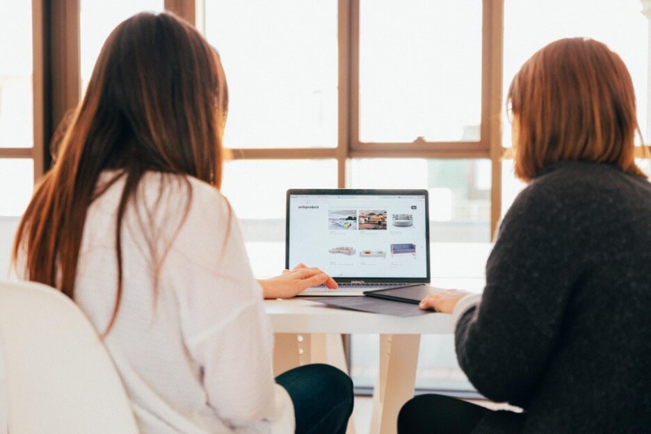 A social media company employee shows a portfolio of past projects to a new client.