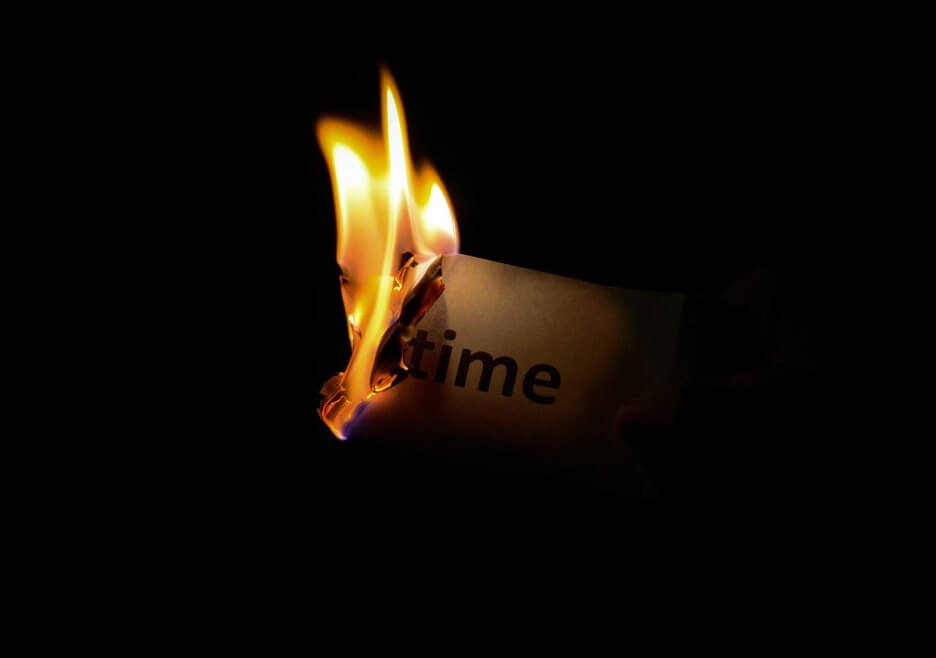This is an image of a burning piece of paper with the word “time” written on it.