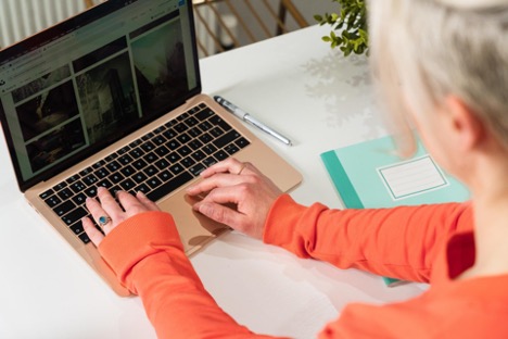 A community manager looks for the perfect image for their social media post on their MacBook.