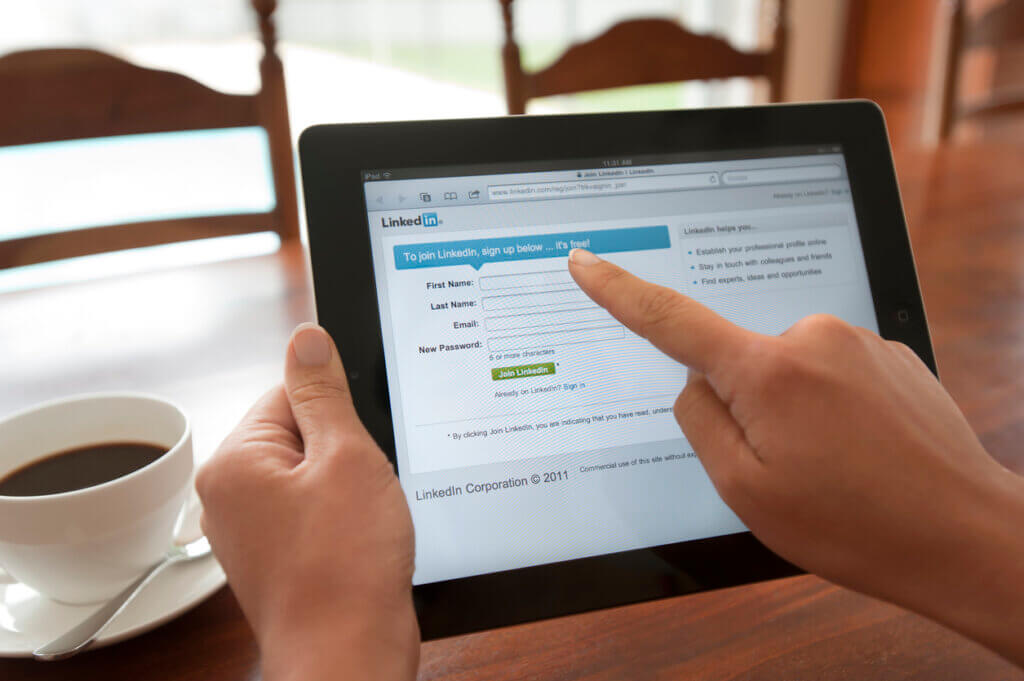 Woman holding an ipad showing the Linkedin login screen